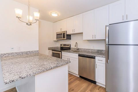 A kitchen with a granite countertop and stainless steel appliances.