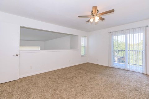 A room with a ceiling fan and carpeted floor.