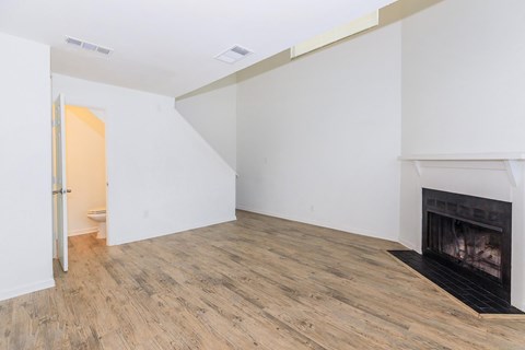 A room with a fireplace and wood flooring.