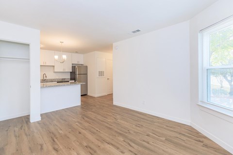 A kitchen with white cabinets and a refrigerator is visible through a doorway.