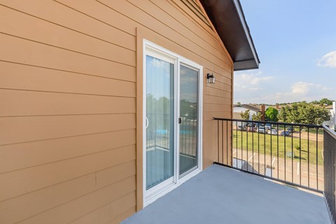 A balcony with a sliding glass door and a black railing.