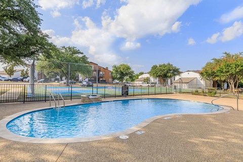 A small pool surrounded by a fence and trees.
