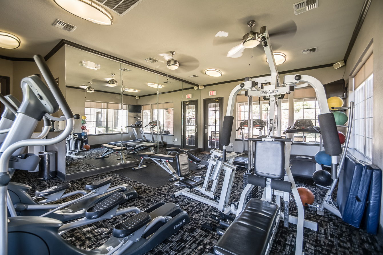 Exclusive Fitness Center with cardio machine and free weights at Fountains of Denton Apartments in Denton, TX