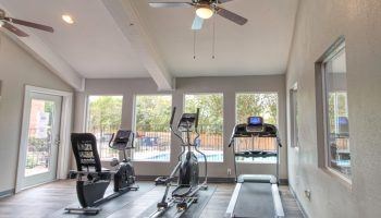 A home gym with a treadmill, elliptical trainer, and stationary bike.