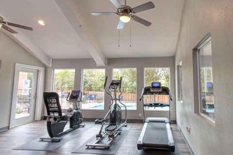 A spacious gym with a variety of equipment including treadmills, elliptical machines, and a weight bench.