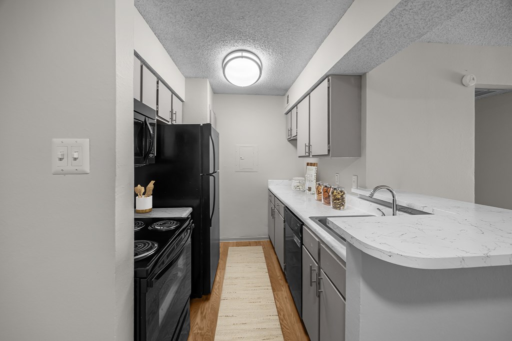 A kitchen with a black refrigerator and a white counter top.