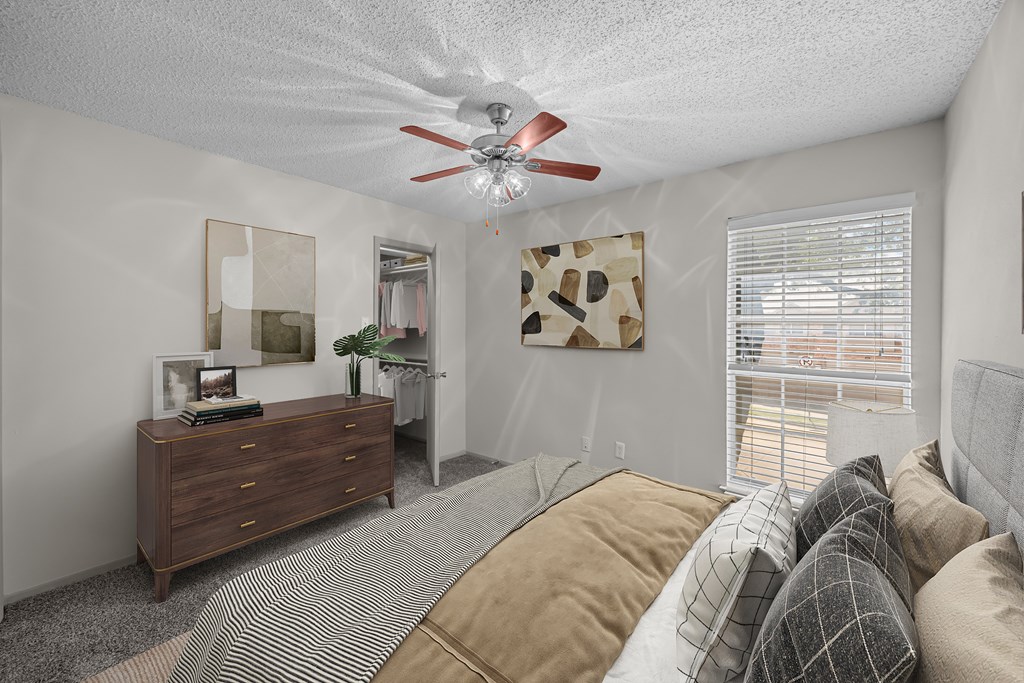 A bedroom with a bed, dresser, and window.