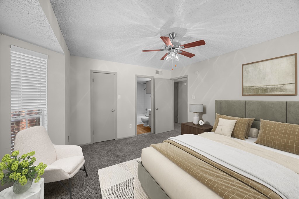 A bedroom with a bed, chair, and a ceiling fan.