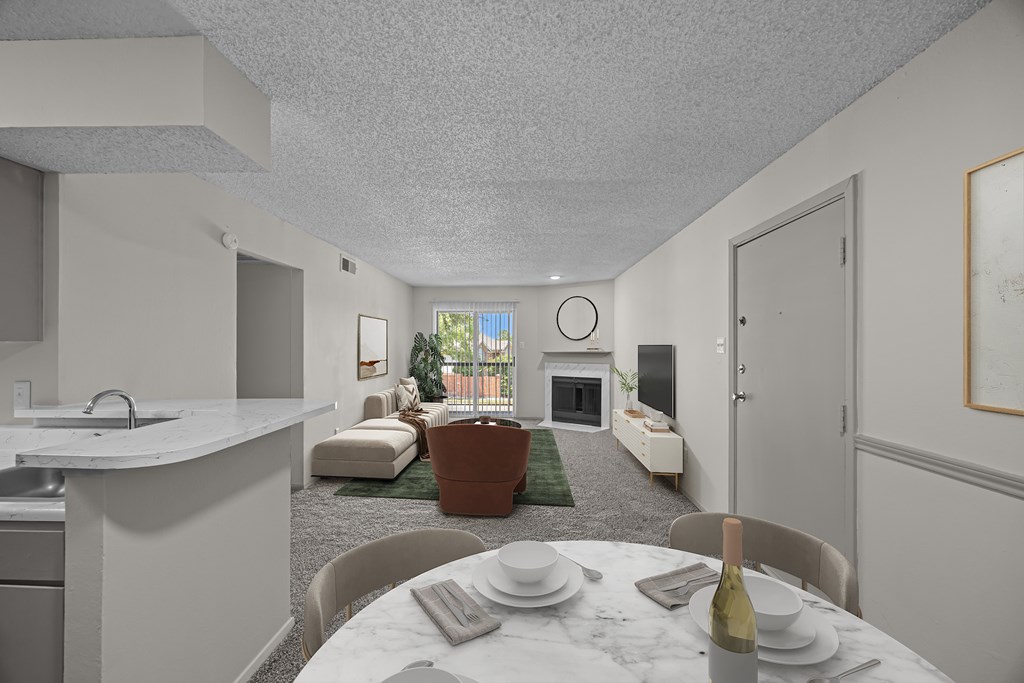 A dining table set for two with a bottle of wine on it.