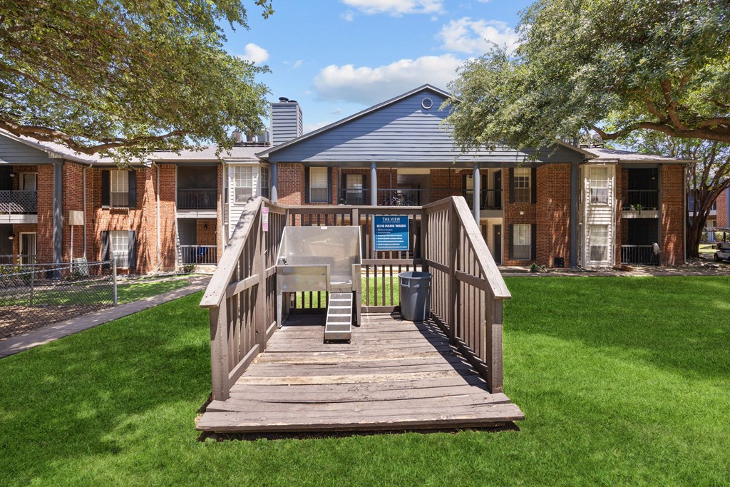 A wooden deck leads to a building with a blue roof.