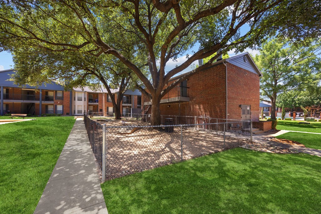 A tree in front of a building with a fence around it.