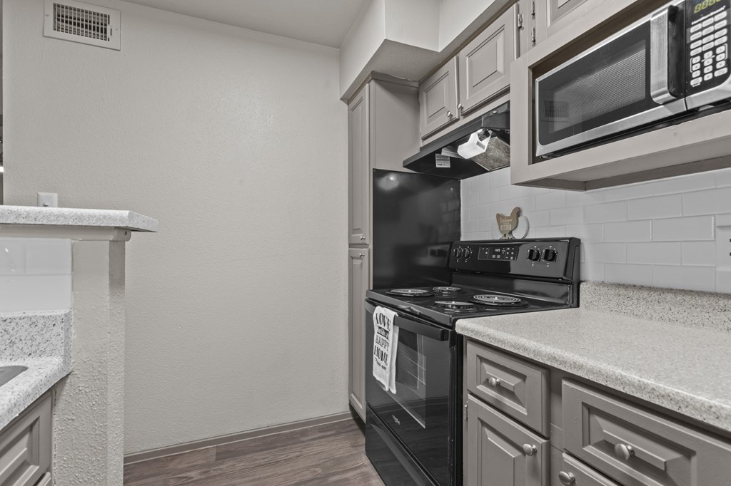 A kitchen with a black oven and microwave above it.at Rock 35, Round Rock, 78681