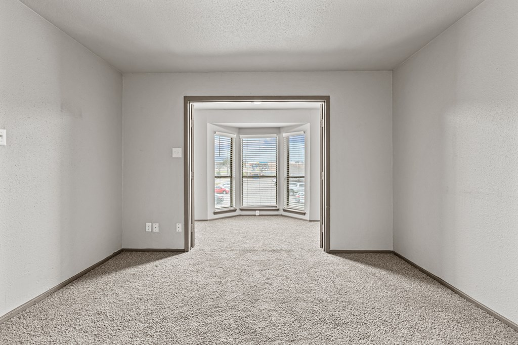 A room with a carpeted floor and a doorway leading to a balcony.at Rock 35, Round Rock, Texas