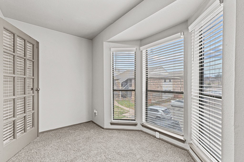 A room with a carpeted floor, a window with blinds, and a door with a window.at Rock 35, Round Rock