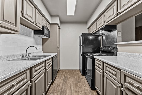 A kitchen with a black refrigerator and a white countertop.