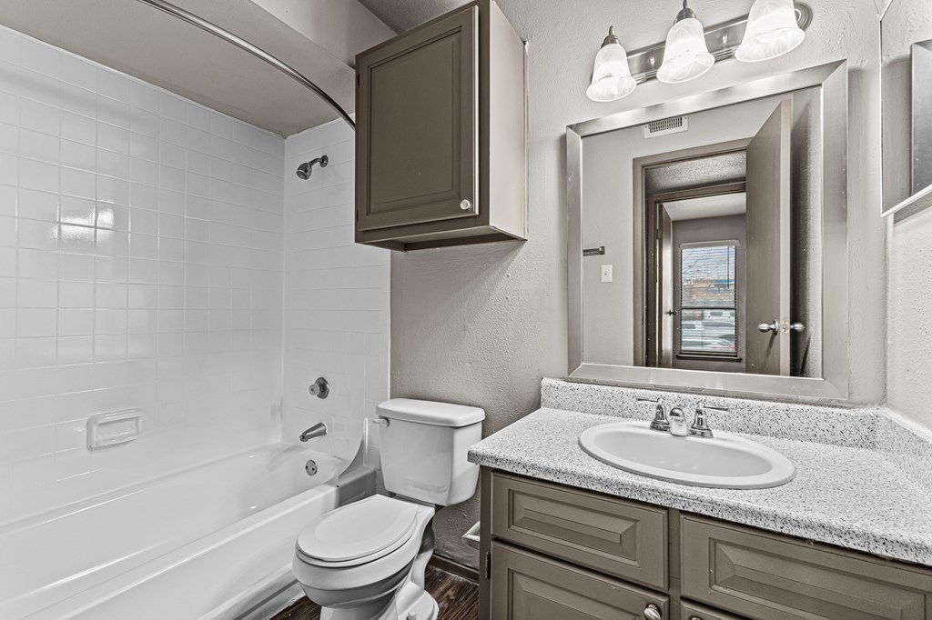 A white bathroom with a toilet, sink, and mirror.at Rock 35, Round Rock, 78681