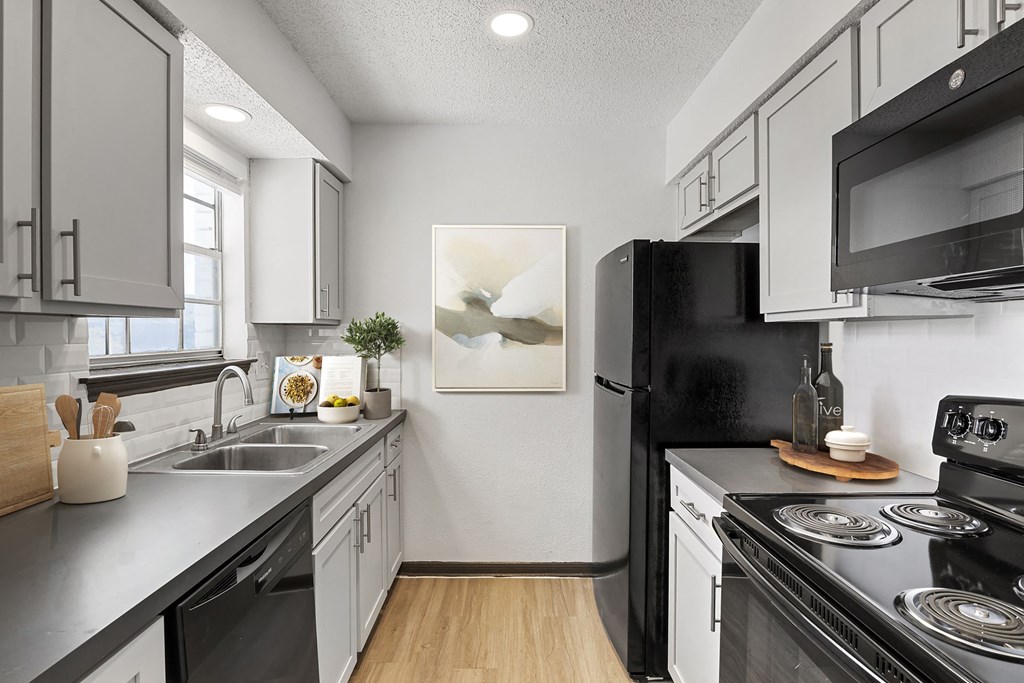 a kitchen with white cabinetry and black appliances at Tradewinds, Texas, 78239