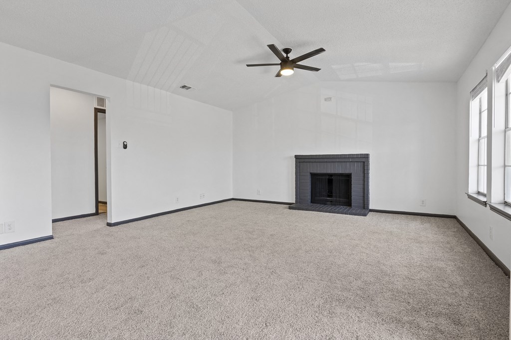 an empty living room with a fireplace and a ceiling fan