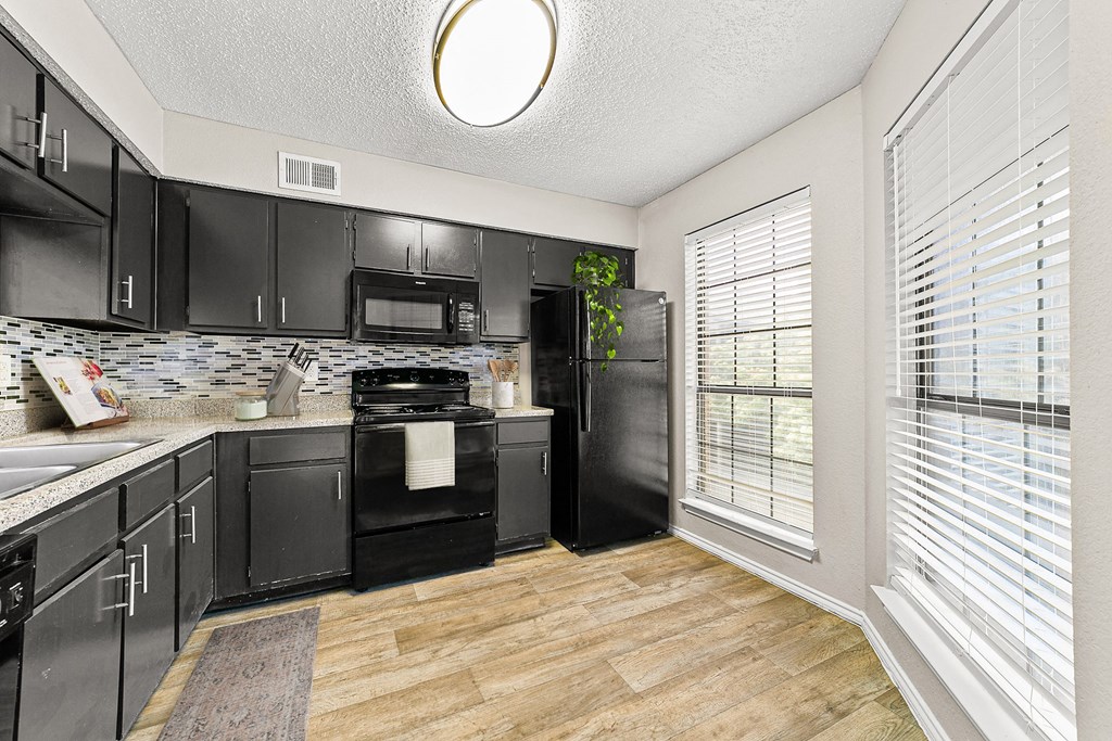 a kitchen with black cabinets and a large window