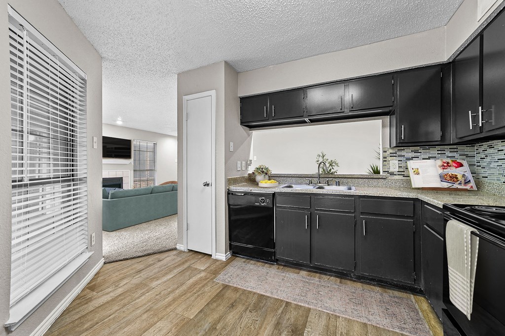 a kitchen with black cabinets and a sink and a window