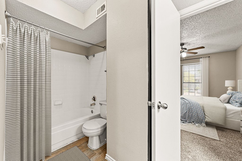 an open bathroom with a bed and a toilet in a bedroom