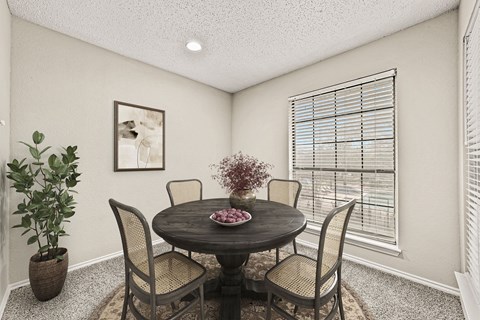 a dining room with a table and chairs and a window at Legacy Apartments in Plano, TX