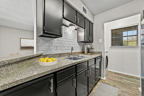 a kitchen with granite counter tops and black cabinets