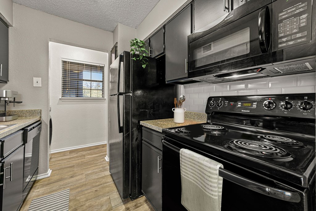 a kitchen with black appliances and a black refrigerator at Legacy Apartments in Plano, TX