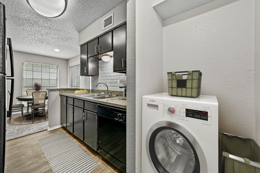 a kitchen with a washing machine and a washer and dryer at Legacy Apartments in Plano, TX