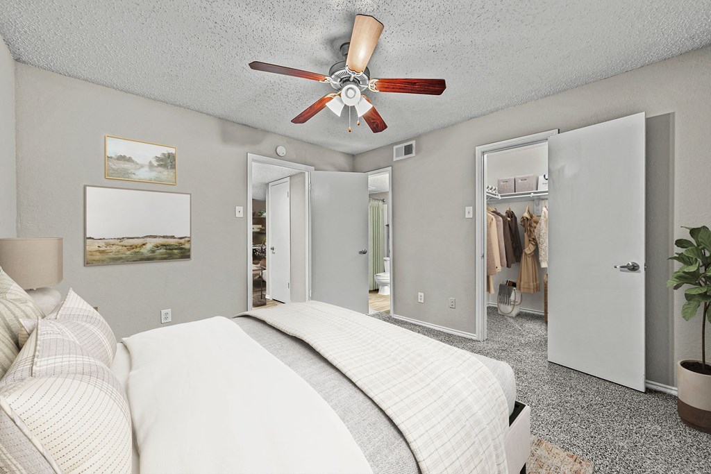 a bedroom with a bed and a ceiling fan at Legacy Apartments in Plano, TX