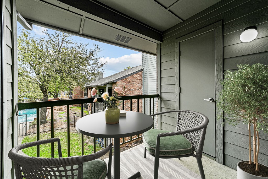a patio with chairs and a table on a balcony at Legacy Apartments in Plano, TX