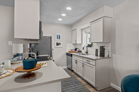 a kitchen with white cabinets and a white counter top and a sink