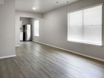 an empty living room with a large window and a white refrigerator  at Sunset Heights, San Antonio