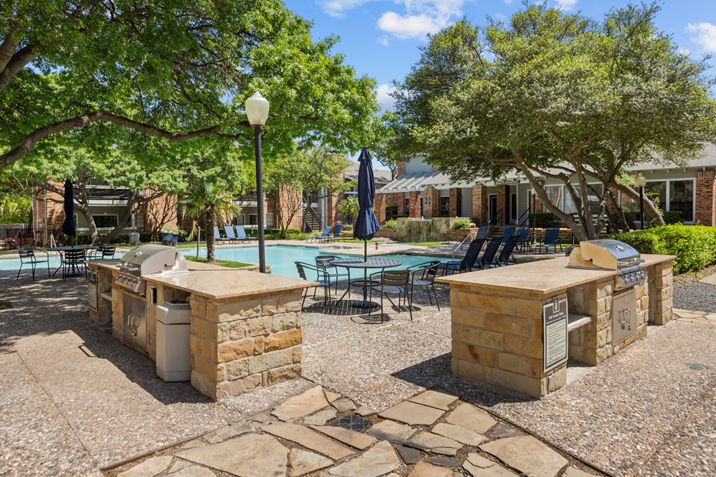 A pool surrounded by stone pillars and chairs.