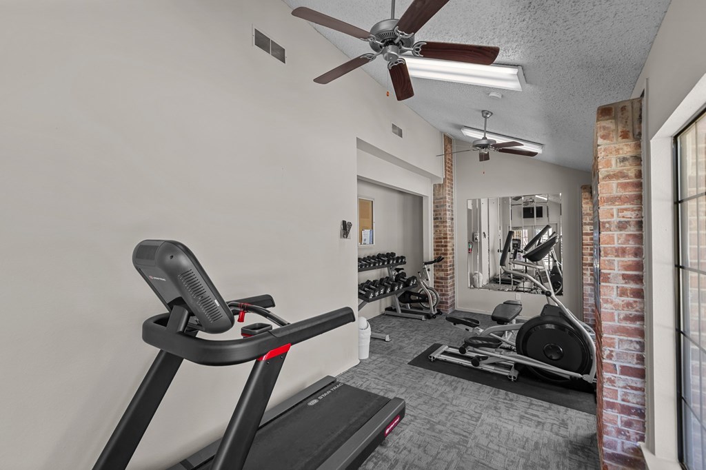 A treadmill is in a room with a fan and exercise equipment.