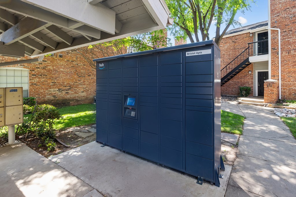 A blue storage unit is on a concrete slab in front of a brick building.