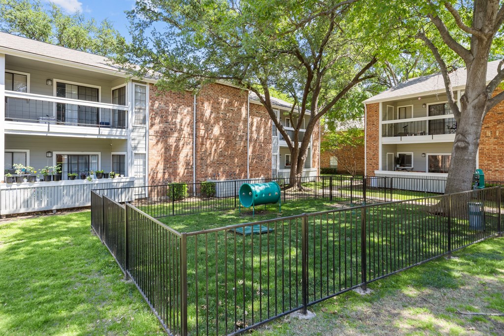 A black fence surrounds a green lawn.