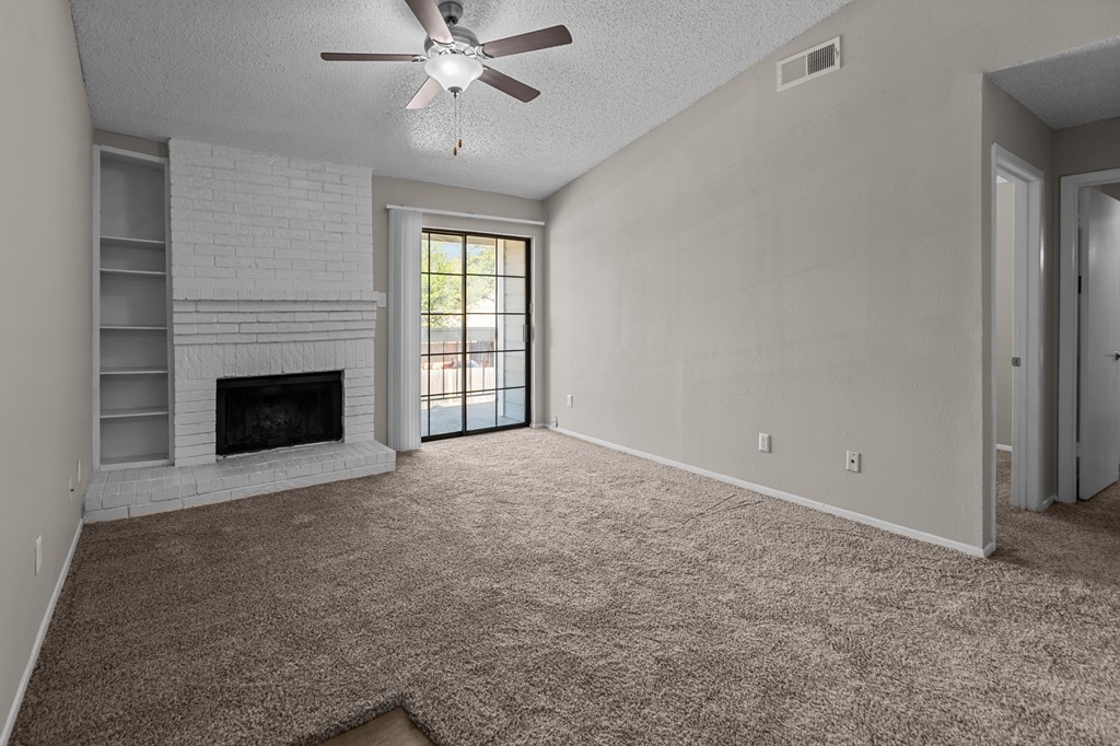 A living room with a fireplace and a ceiling fan.