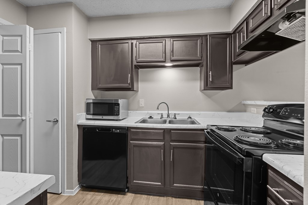 A kitchen with brown cabinets and black appliances.