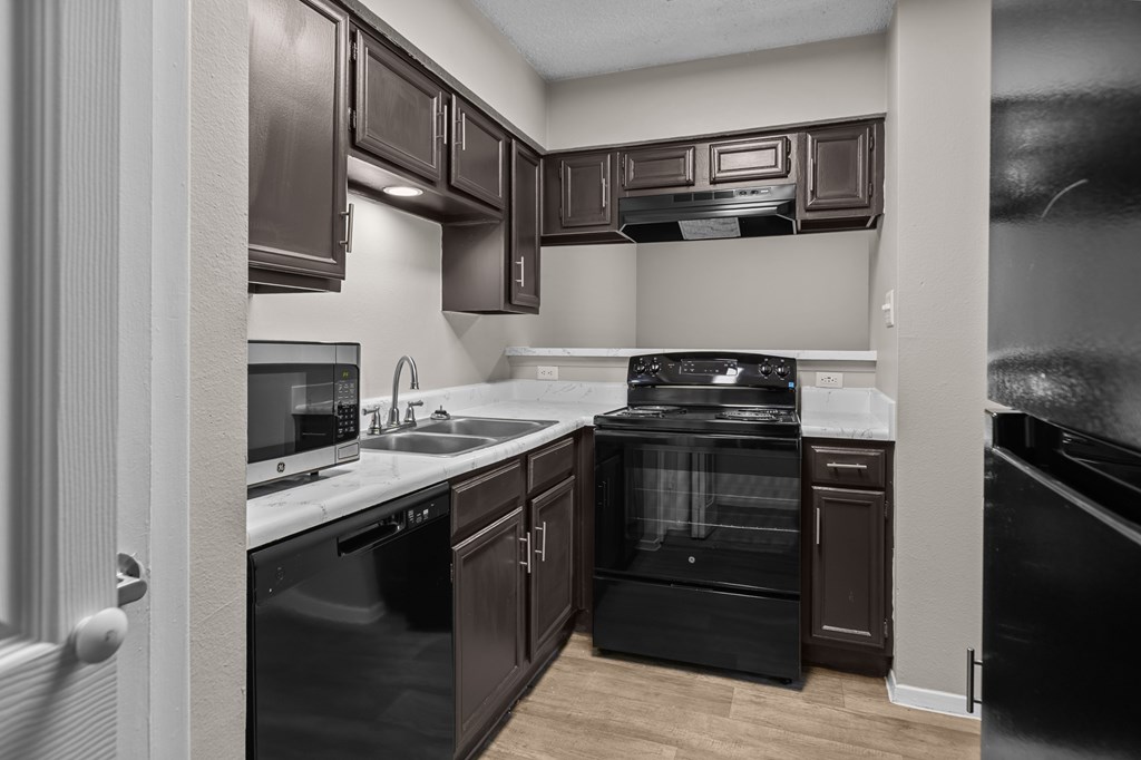 A black and white photo of a kitchen with a black oven.