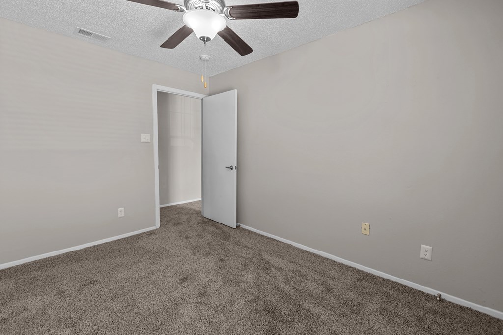A room with a ceiling fan and carpeted floor.