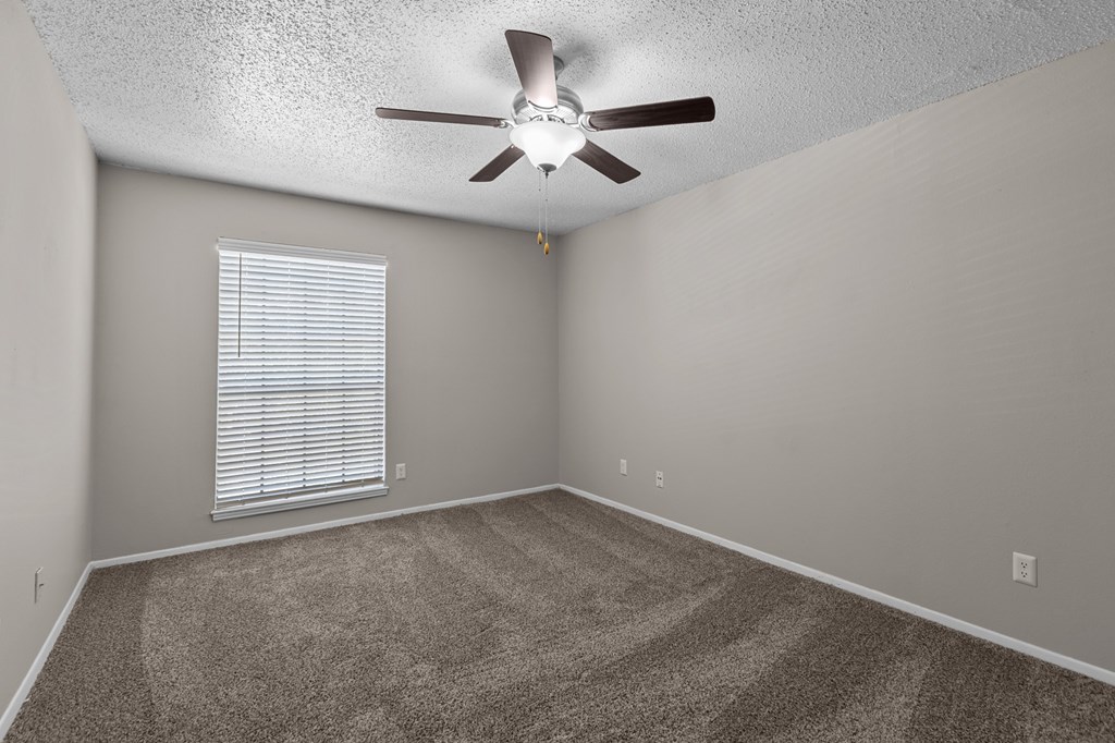 A room with a ceiling fan and a window with blinds.