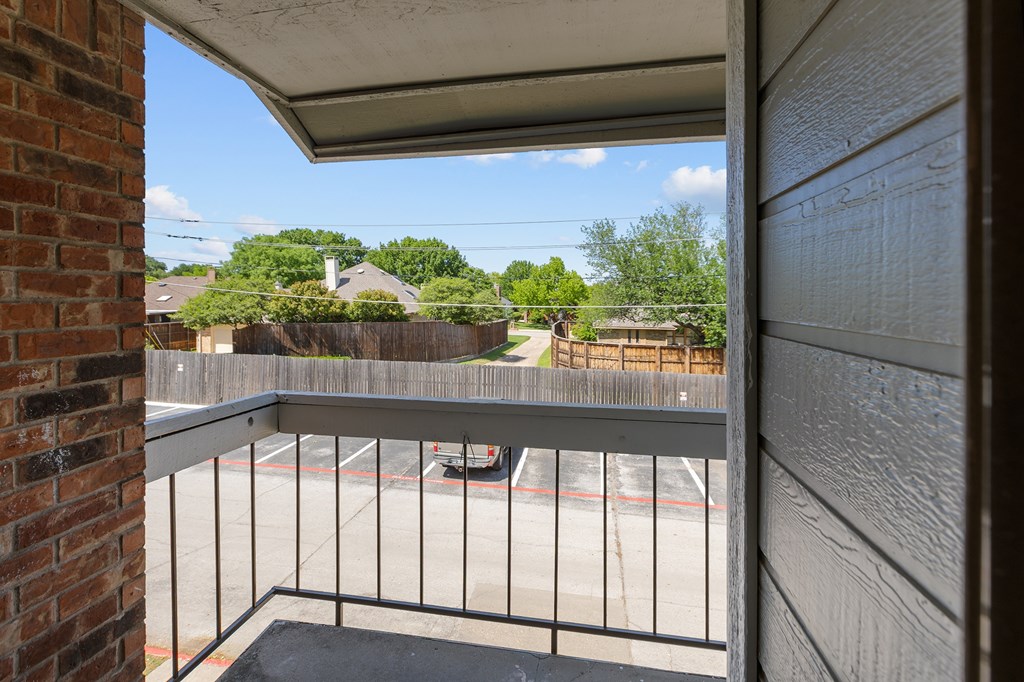 A balcony with a metal railing and a brick wall.