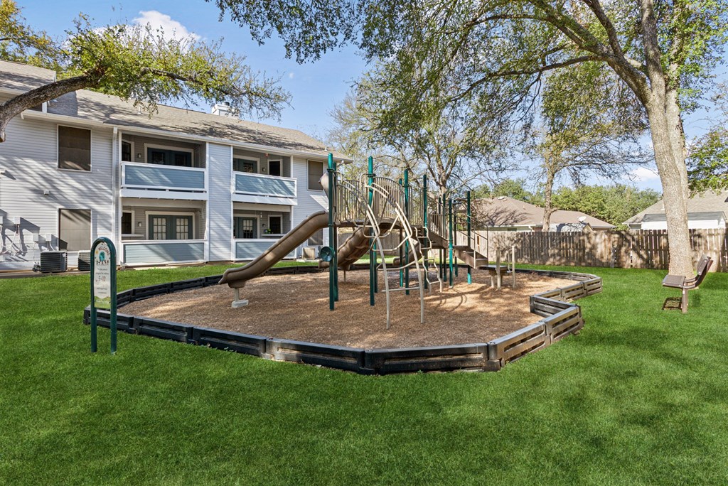 A playground with a slide and swings in a backyard.