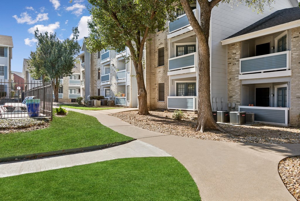 Apartment complex with a grassy area and a walkway.