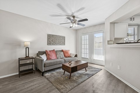 A living room with a grey couch, a wooden coffee table, and a ceiling fan.