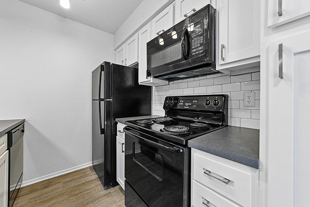 a kitchen with white cabinets and black appliances at Vesper, Dallas, Texas