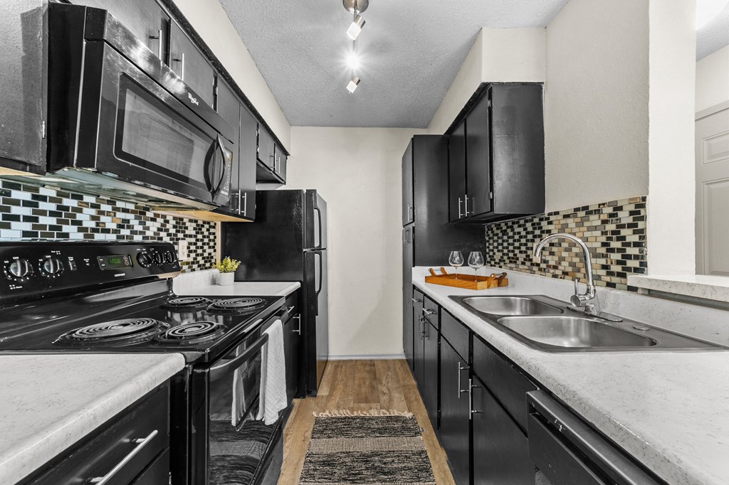 a kitchen with black cabinets and white countertops and a black and white checkered tile at Vesper, Dallas, Texas