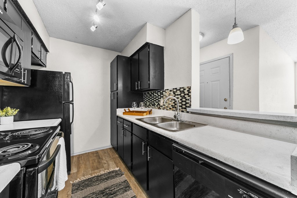 a kitchen with black cabinets and white countertops  at Vesper, Dallas, 75254