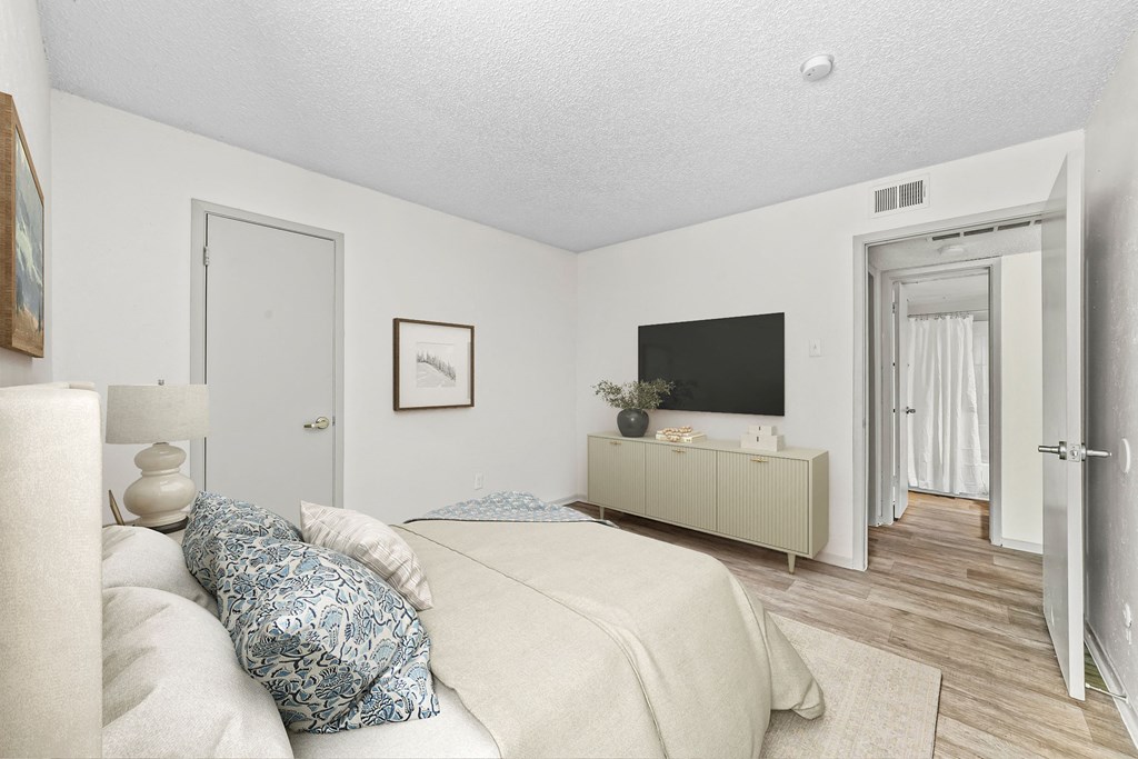 a bedroom with white walls and a large white bed with blue and white pillows  at Vesper, Dallas, TX, 75254